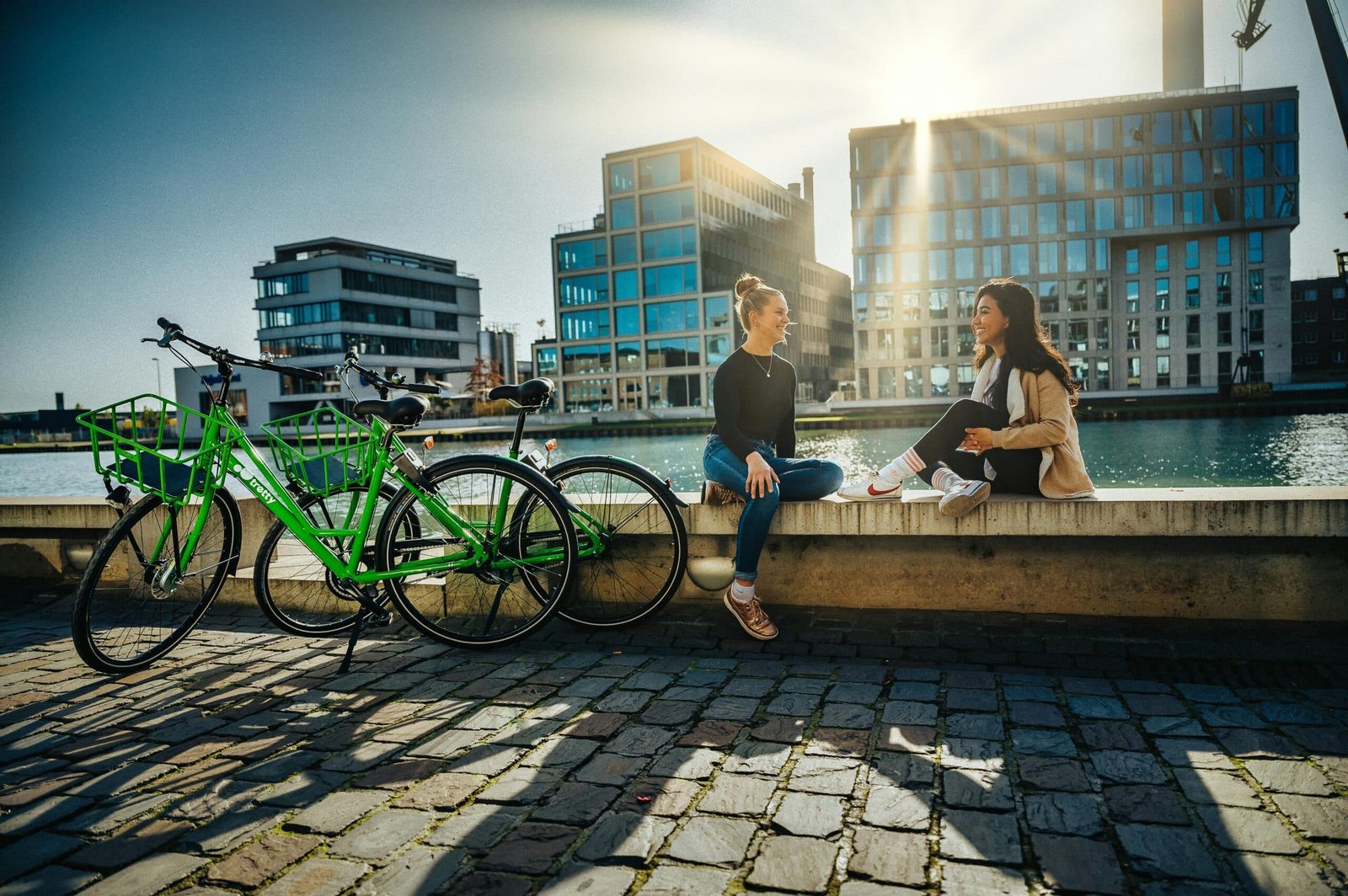 two women sitting on a ledge next to bicycles